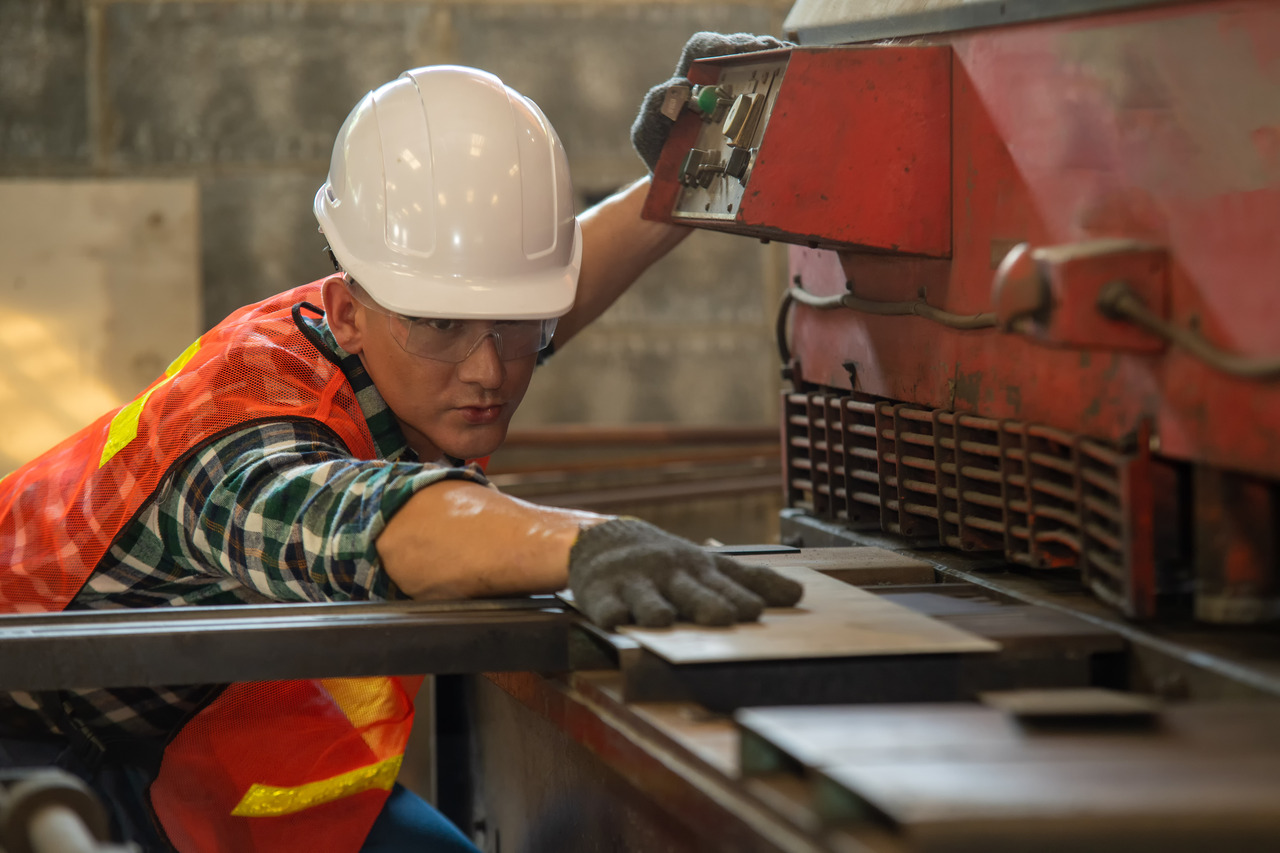 Worker in uniform operating in manual lathe in metal industry fa