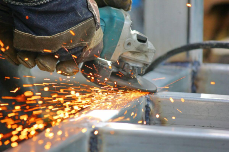 Worker fabricating steel components in an industrial setting, highlighting precision metalworking and structural steel production processes.