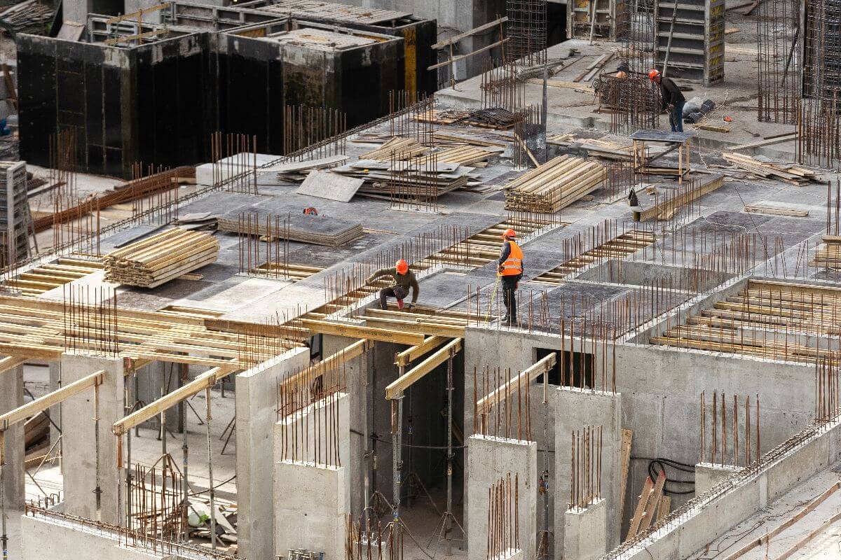 Construction workers installing reinforcement bars and formworks on a concrete building site