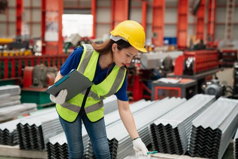 Worker inspecting angle bars during quality control in a steel facility